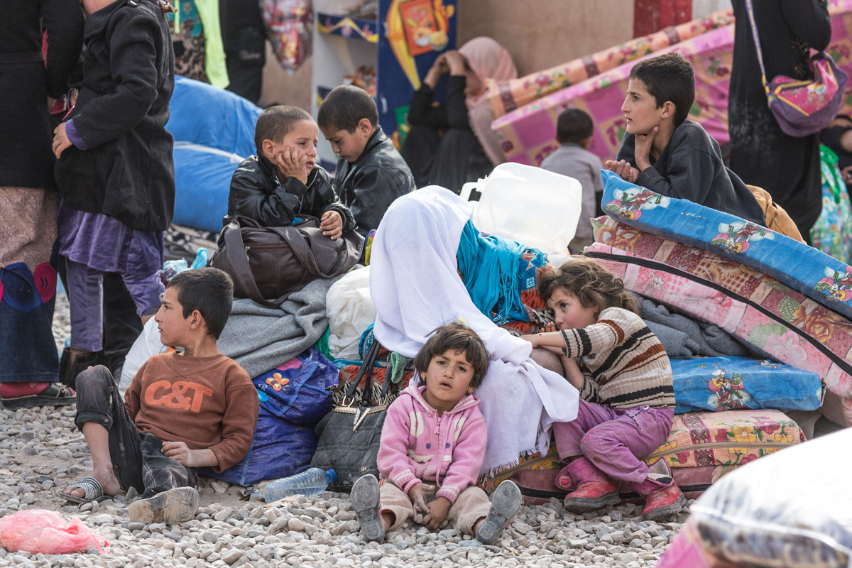 Children who have recently arrived at Debaga Camp after fleeing Mosul wait outside on mattresses. Without enough tents, many have been sleeping here and in corridors of a local school that is within the camp’s boundaries.