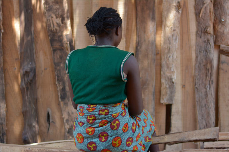 child soldier sitting down, stripped of her rights as a child