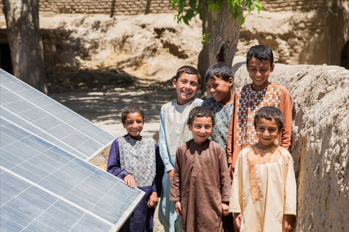 Children stand by a solar panel that powers a drinking water decontamination system in the Langar district in Afghanistan.