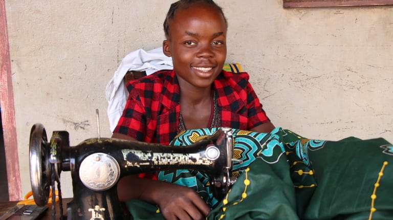 Mwila sewing clothing with her sewing machine