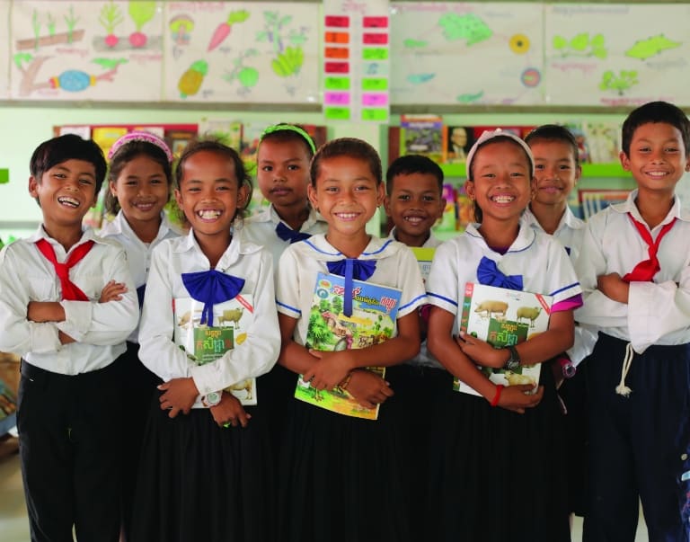 School children holding books and smiling