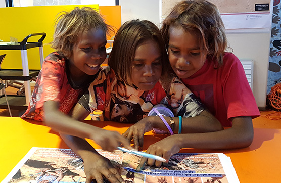 Three First Nations children doing school work together