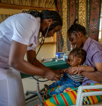 A nurse checking on a toddler with their mother