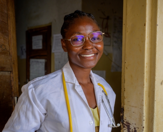 A female nurse in Zambia standing by a door looking at camera