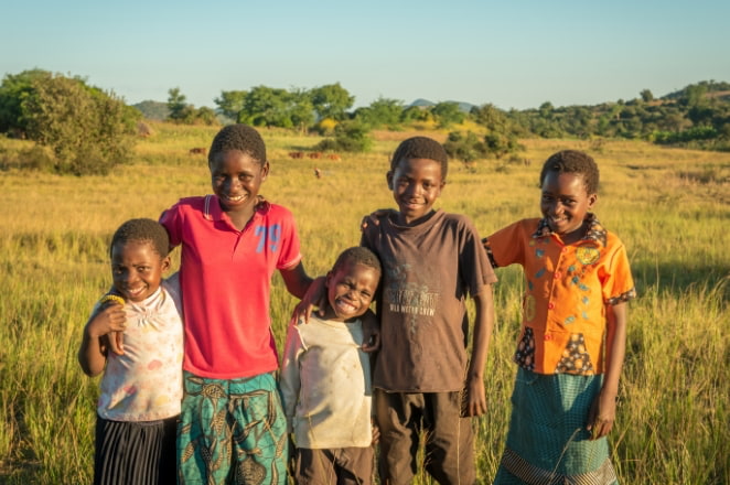 5 children standing in a field smiling