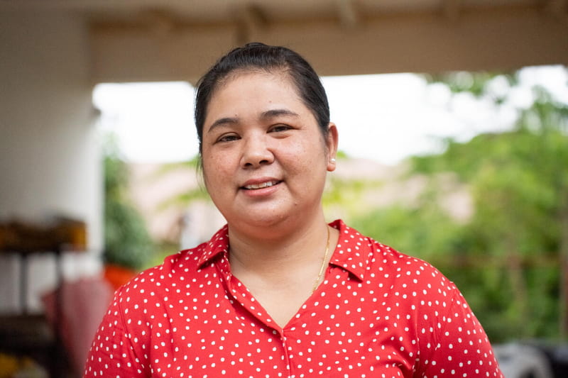 A close-up of Cholada, a Thai woman who survived the tsunami, smiling bravely from a face filled with emotion.