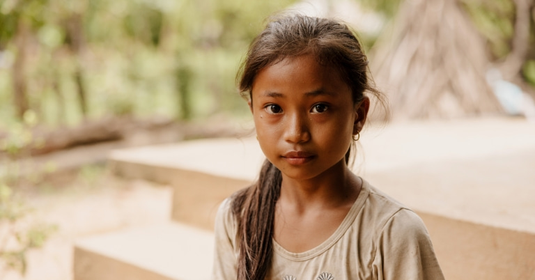 Young girl with hair draped over shoulder looking at the camera