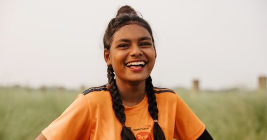 Young girl from Bangladesh in soccer clothes smiling at camera