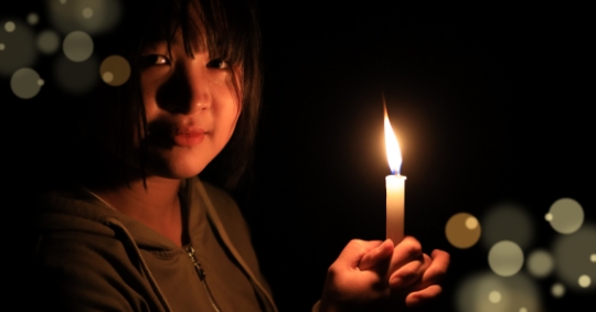Young girl looking at camera holding a candle