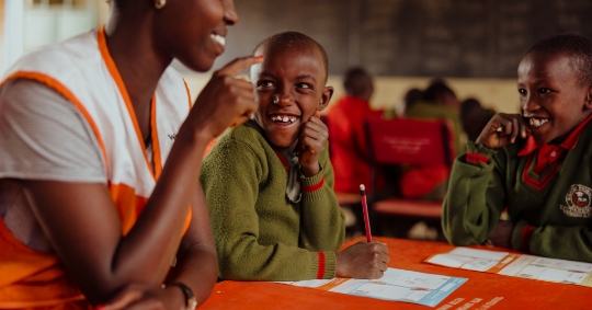 Young Kenyan boy in school smiling at teacher