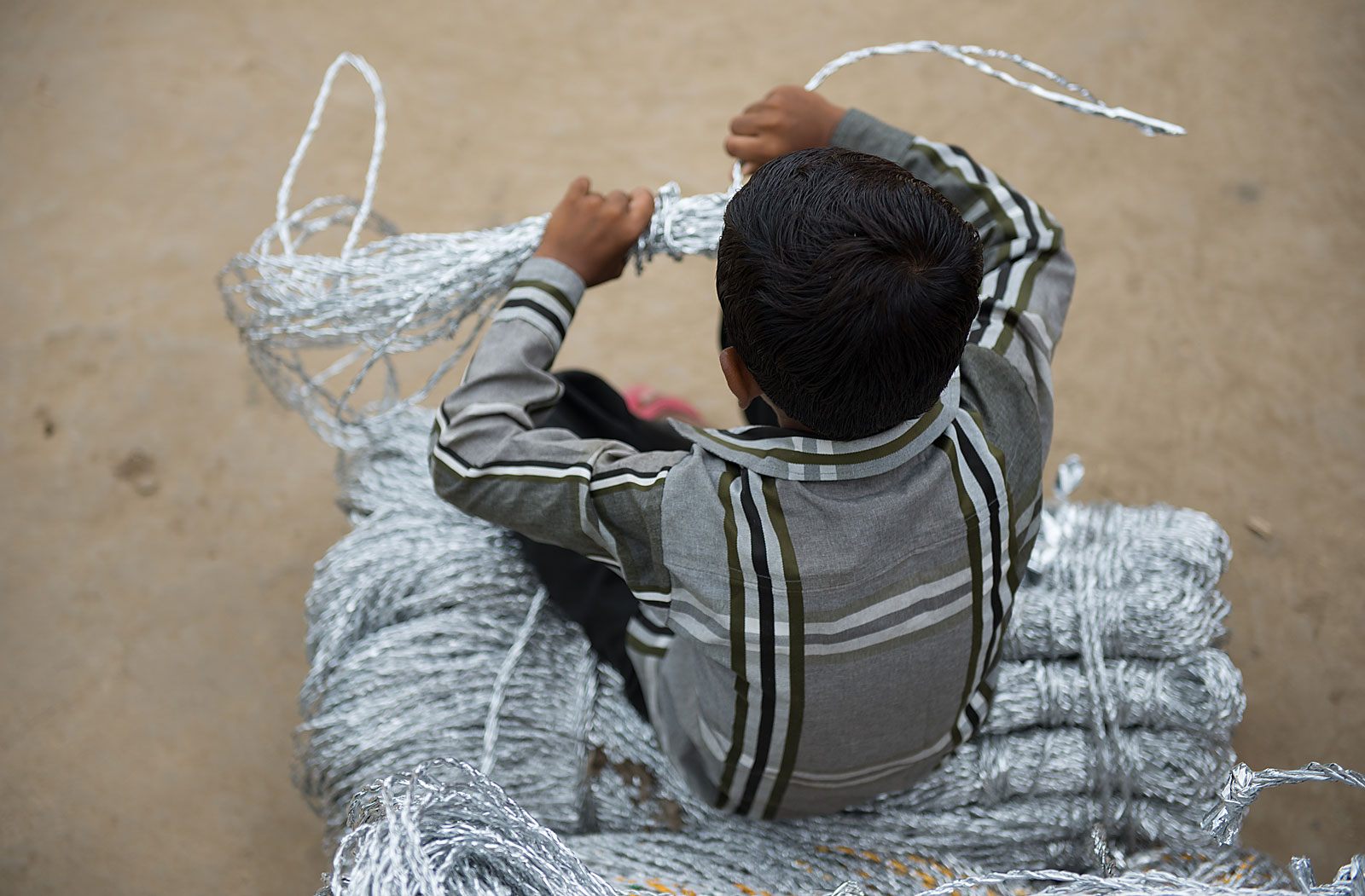 Boy who is a victim of child labour sits on a bundle of ropes