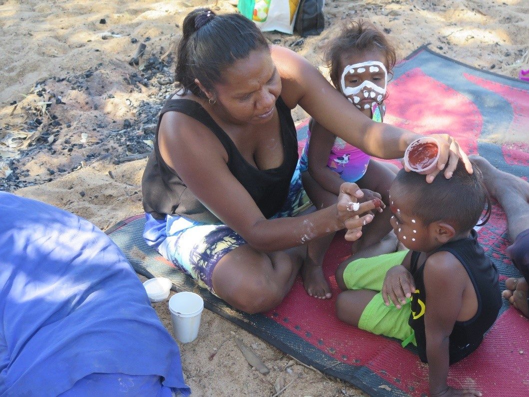 Aboriginal Woman applies traditional face paint to two Aboriginal children for the Australia Program 4