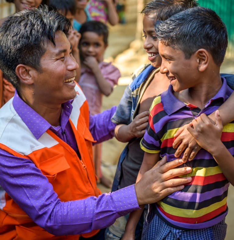 Two young boys sharing a laugh with a World Vision worker