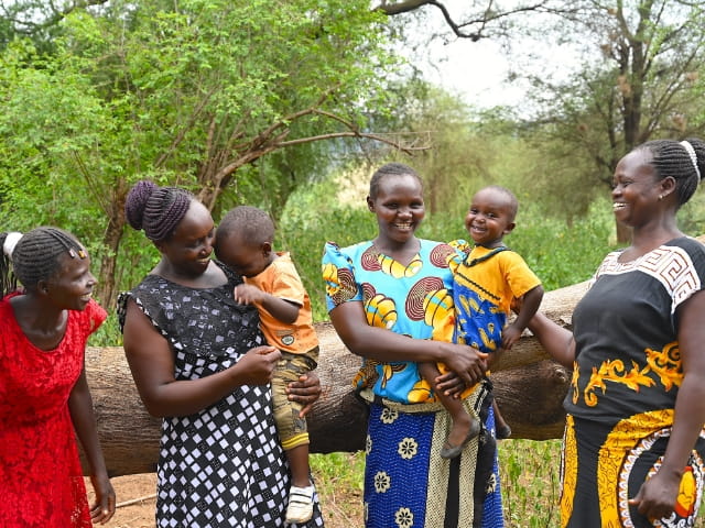 Women holding children in a forest