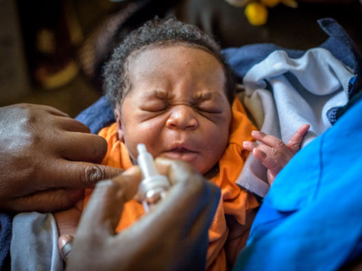 An infant receives an oral polio immunisation at a health centre in Uganda.