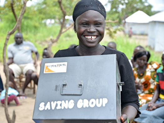 Joyce displays a community savings box where members in her group keep their weekly savings.