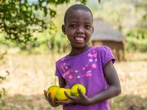 Kamama picks oranges in her family’s orchard in Kenya. With their orange, guava, mango and lemon trees, healthy food is never far away.