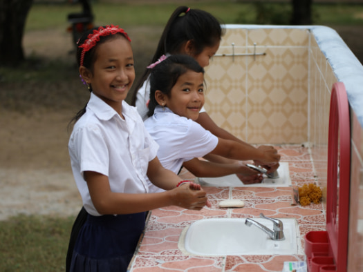 Young Cambodian students demonstrate how to wash their hands with their newly
installed handwashing stations.
