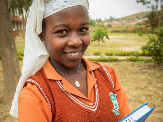 Sarah, from Zimbabwe, holds a book that shares her love of learning and a message – stay in school.