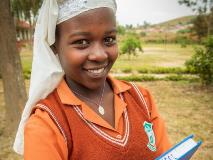 Sarah, from Zimbabwe, holds a book that shares her love of learning and a message – stay in school.