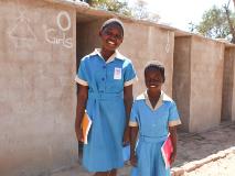 Joan (left) and Shyline (right) in front of their new toilets at their school in Hwange, Zimbabwe.