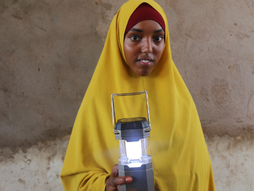 In Somalia, Rahma uses her solar lantern for light to study and walk outside safely when darkness falls.