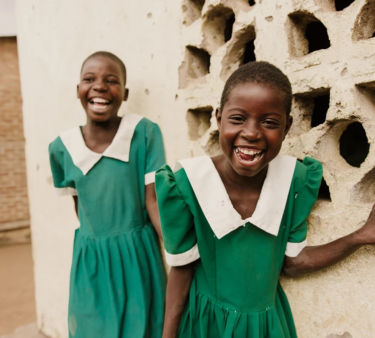 Two smiling girls wearing school uniforms.