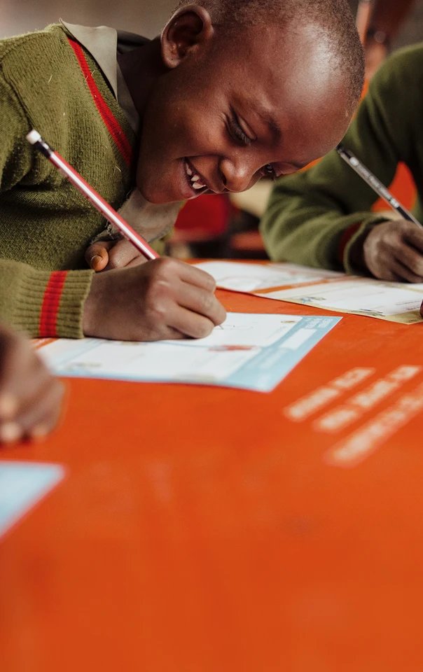 Smiling school boy writing at a table.